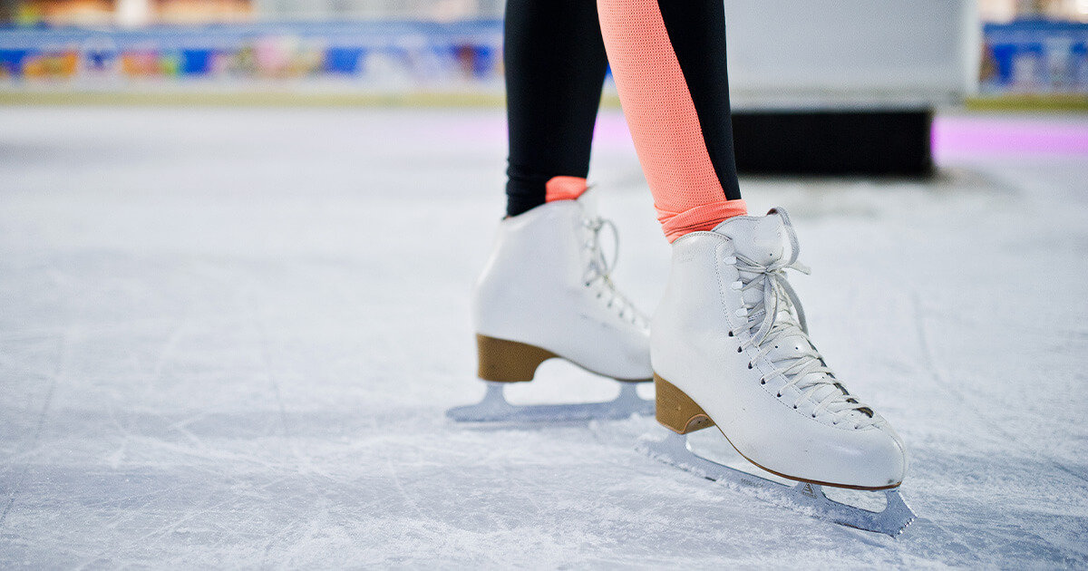 Close up of figure skates on an indoor ice rink.\
